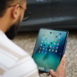 Man holding a tablet with colorful app icons.