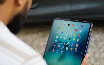 Man holding a tablet with colorful app icons.