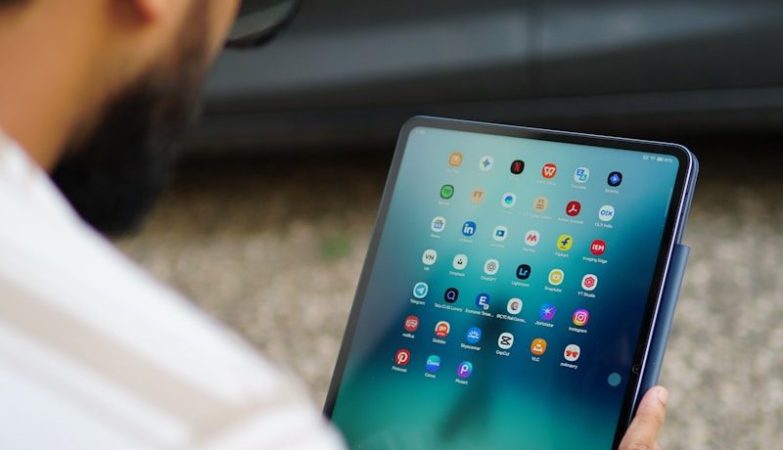 Man holding a tablet with colorful app icons.