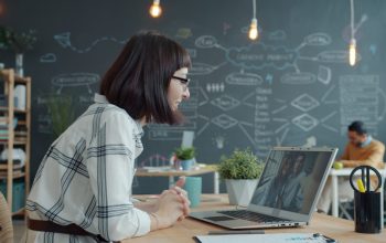 Woman video conferencing with colleagues in a modern office.