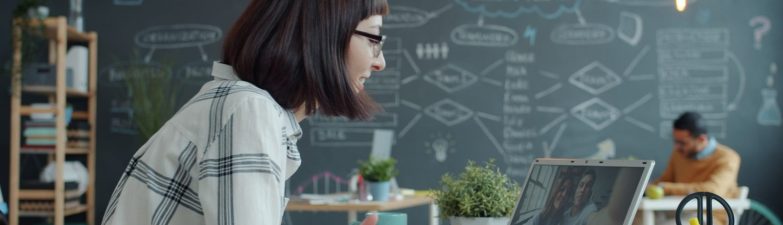 Woman video conferencing with colleagues in a modern office.