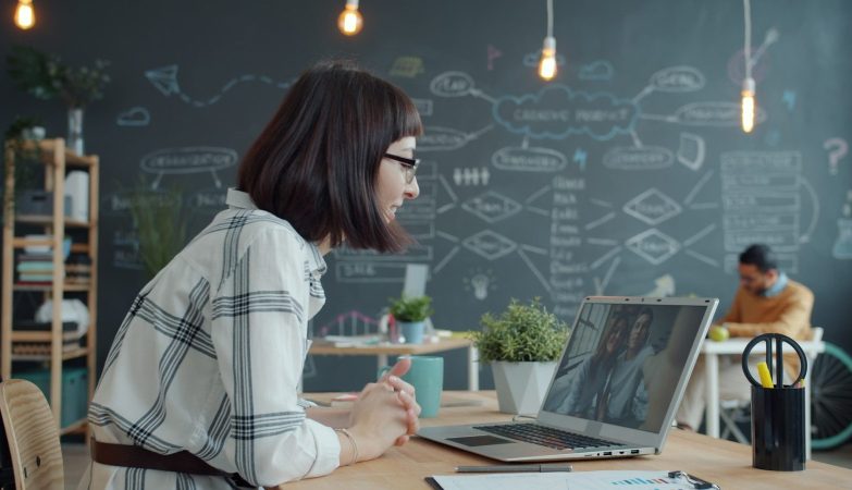 Woman video conferencing with colleagues in a modern office.