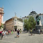 a group of people walking around a statue in a city