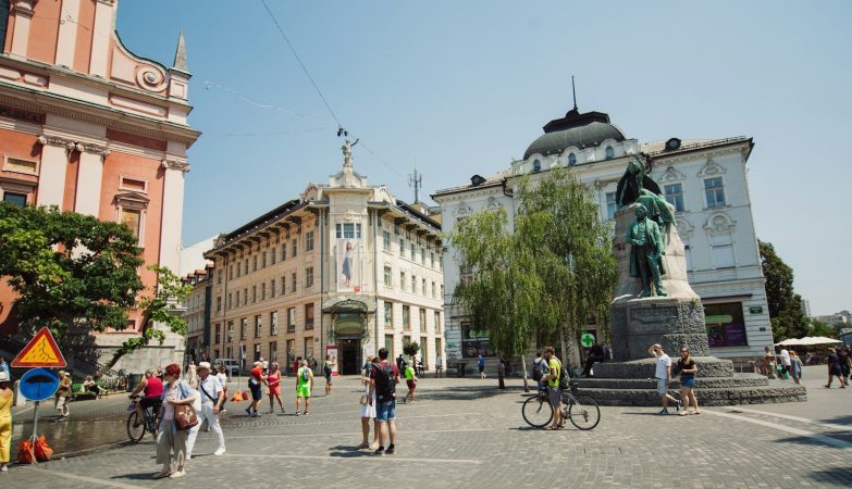 a group of people walking around a statue in a city